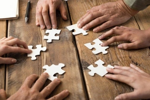 Hands on a table doing puzzle. Innovation - Inter-American Development Bank - IDB