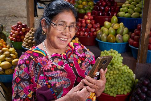 Woman smiles with a cellphone- Financial Development - Inter American Development Bank - IDB