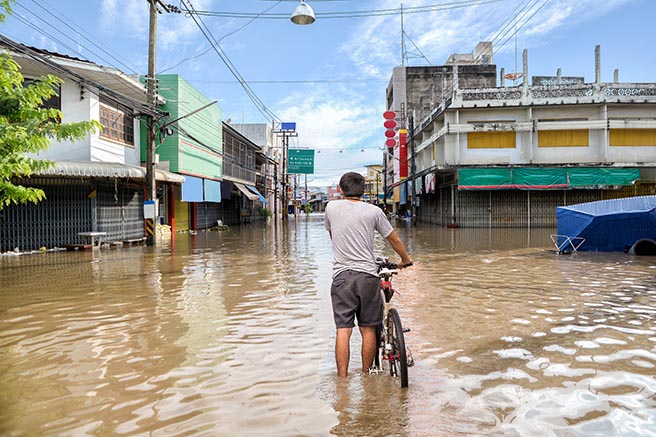 A boy on a bicycle in a flooded street. Sustainability - Inter-American Development Bank - IDB