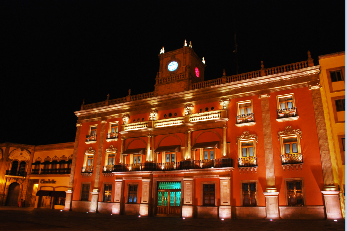 An illuminated building with a clock tower. Inter-American Development Bank