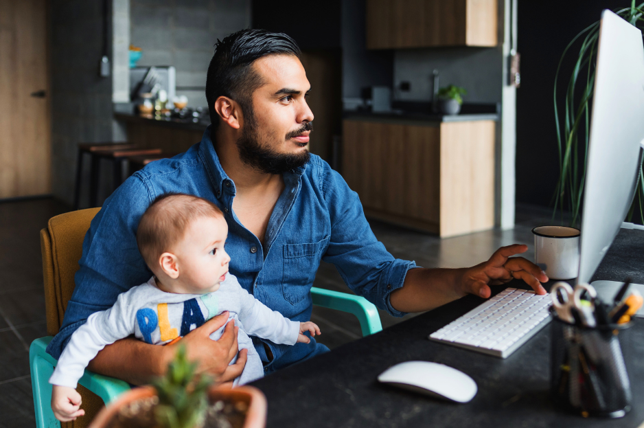 Padre trabajando en la computadora con su bebé