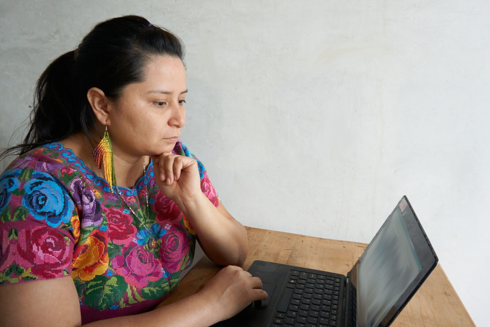 Guatemalan ladino o mayan woman working on computer in traditional huipil dress