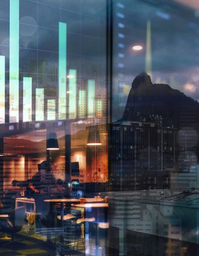 An urban view through a glass window reflecting electronic charts.
