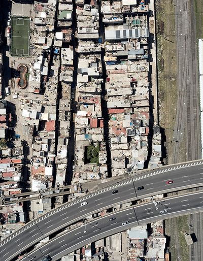Aerial view of a dense urban neighborhood beside railway tracks and an elevated highway.