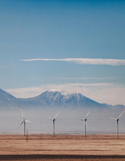 Wind turbines on an arid plain with mountains in the background.