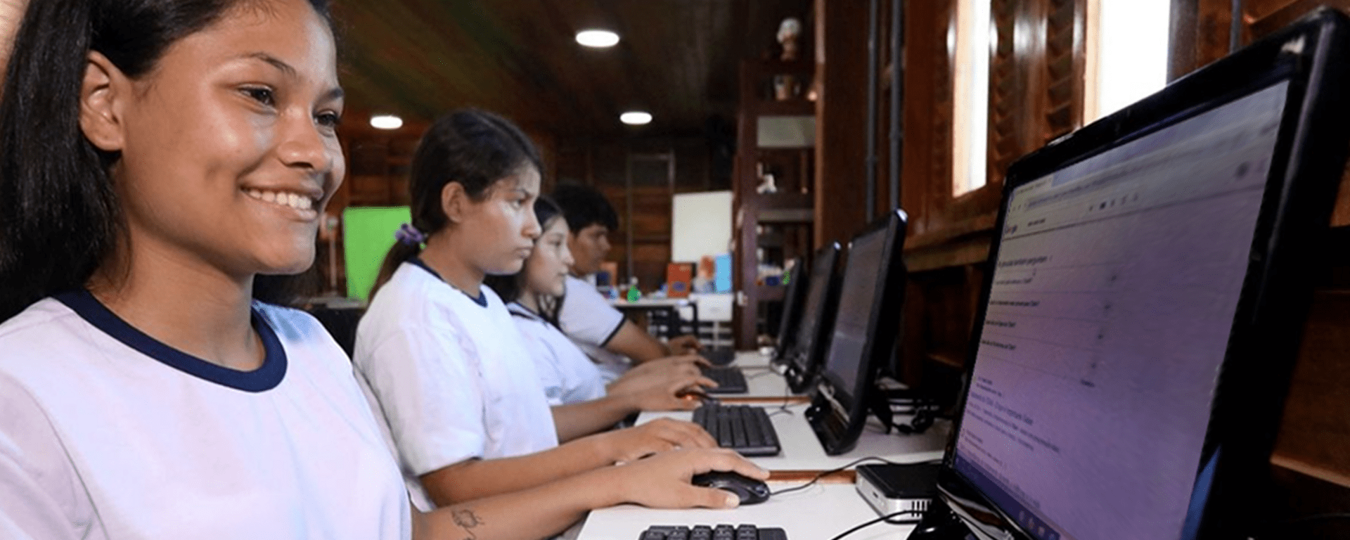 Young brunette woman smiling and looking at a computer screen - Inter American Development Bank - Education