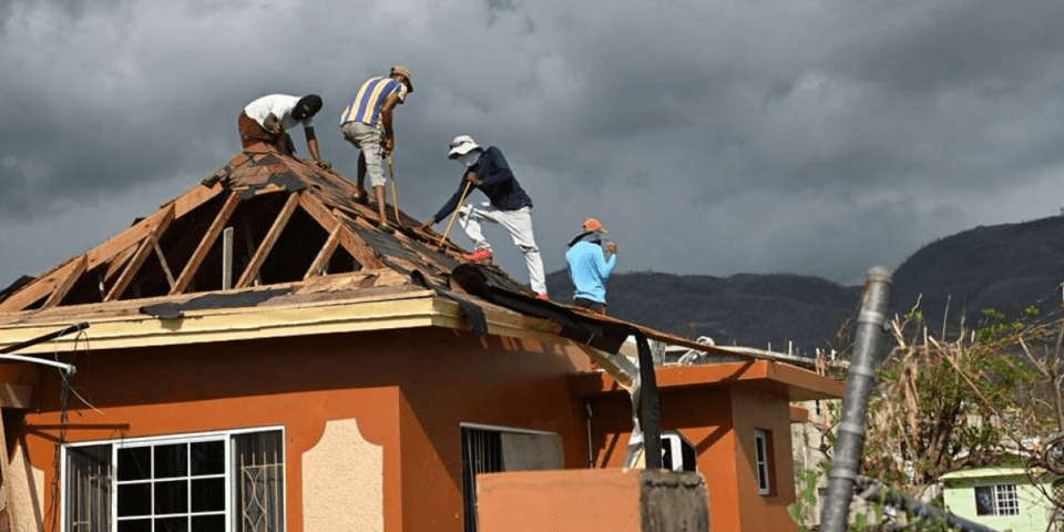 Men on the wooden roof of a house under construction - Inter American Development Bank - Disaster Management