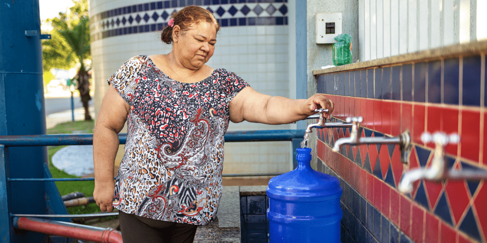 Elderly woman turning on water tap - Inter American Development Bank - Water and Sanitation