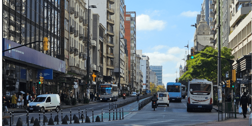 City street with buildings, buses and vehicles around - Inter American Development Bank - Transport Infrastructure