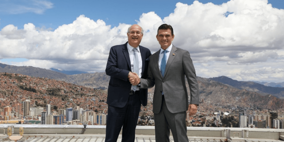 Ian Goldfjan shaking hands with another person, with a landscape in the background - Inter American Development Bank - IDB Group