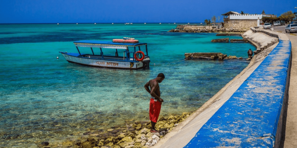 Afro-descendant man looking down at the sand floor, between the sea and the beach - Inter American Development Bank - IDB Impact