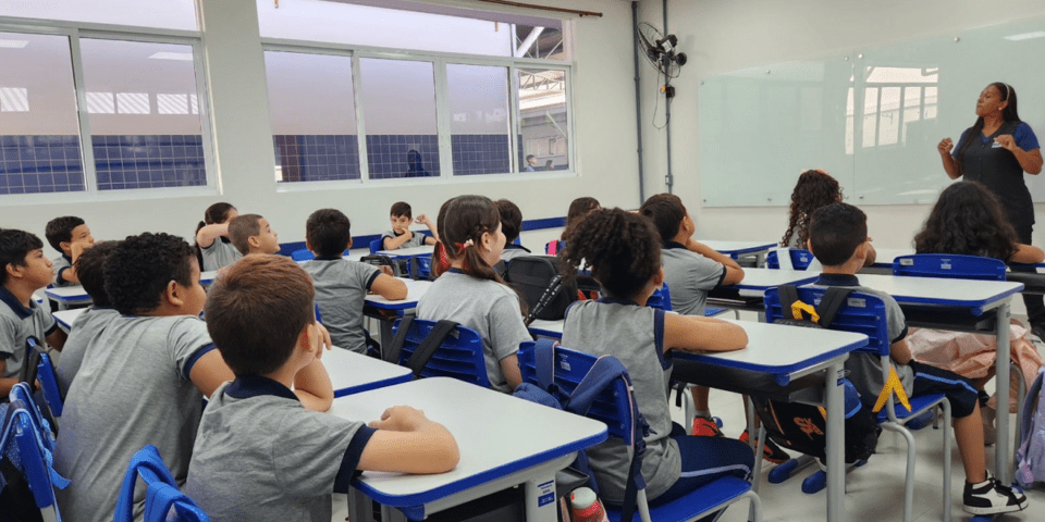 A students group sitting in desks in a classroom - Inter American Development Bank - Education