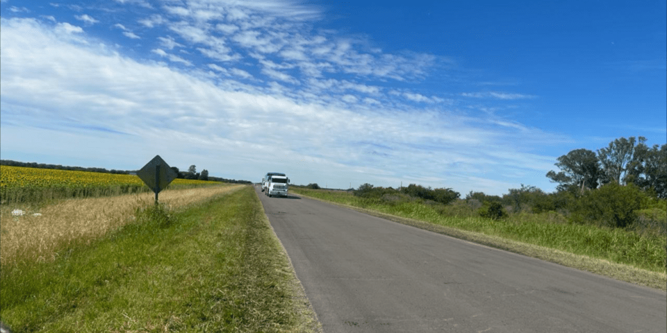 General view of a rural road with a moving vehicle in the background - Inter American Development Bank - Infrastructure Development