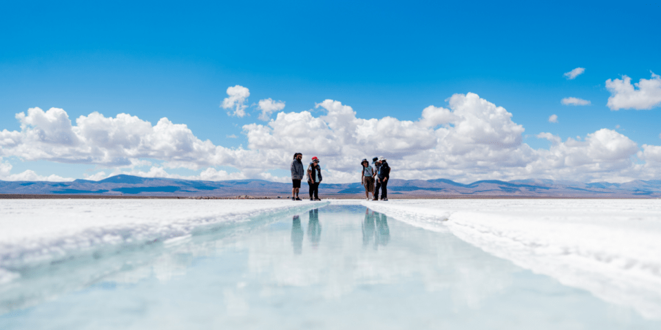General view of a lake with people in the center and salt around it, with mountains on the horizon - Inter American Development Bank - IDB Invest
