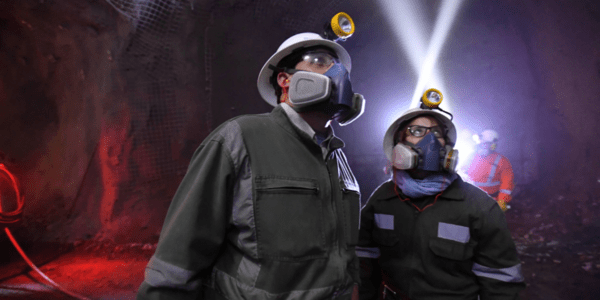Trabajadores inspeccionan una mina subterránea con equipos de seguridad.