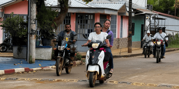 Una mujer conduce una motocicleta con una pasajera.
