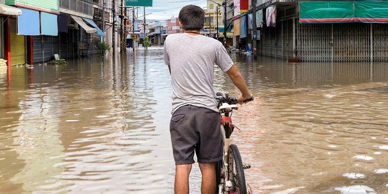 A boy on a bicycle in a flooded street. Environment - Inter-American Development Bank - IDB