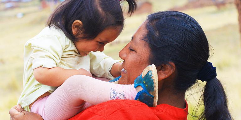 A woman holding a baby smiling. Inclusion - Inter-American Development Bank - IDB