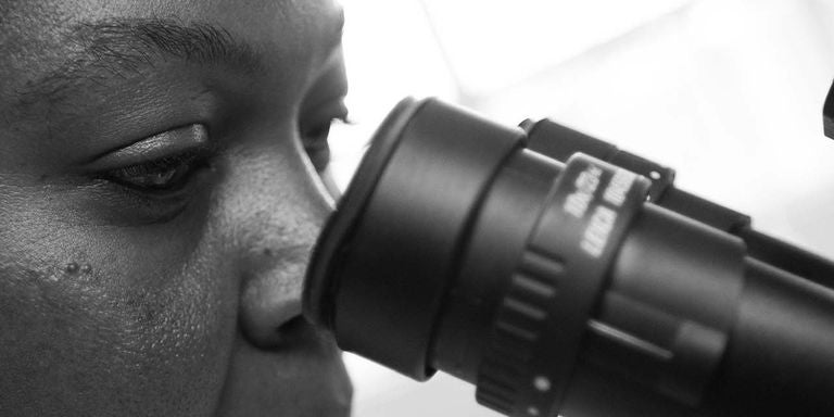 A close-up of a person looking through a microscope