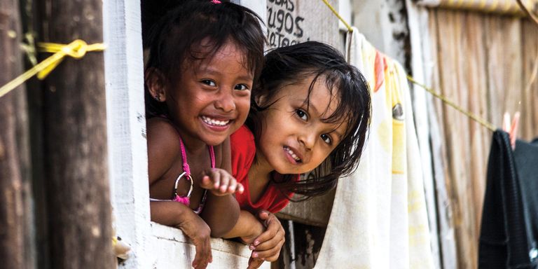 Two children look out a window in a poor neighborhood - Inter-American Development Bank - IDB