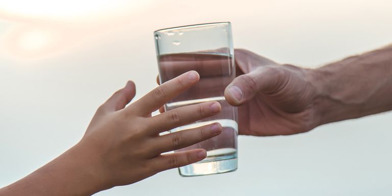 two hands exchanging a glass of water