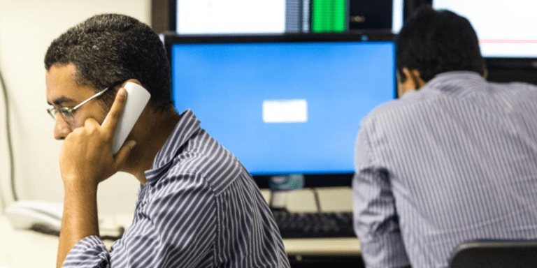 Two men working in a control room, surrounded by computer monitors displaying data and surveillance feeds - Inter-American Development Bank - IDB - Modernization of the State