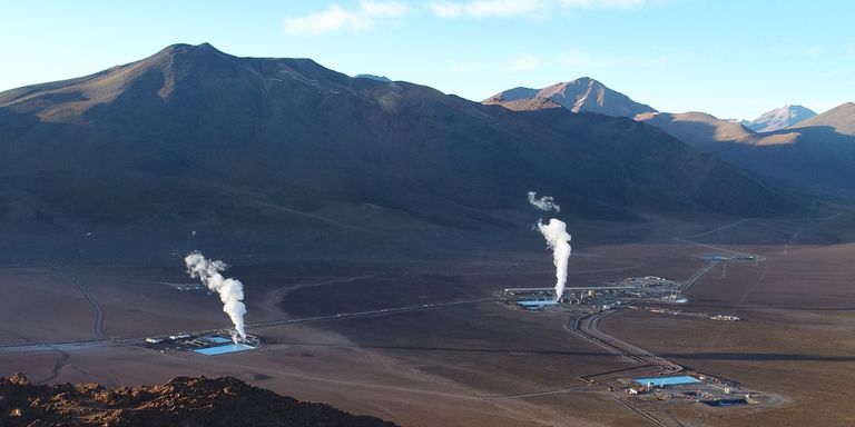 Aerial view of a geothermal power plant in a remote mountainous desert region, with steam rising from two separate facilities nestled between high Andean peaks - Inter-American Development Bank - IDB - Project Procurement