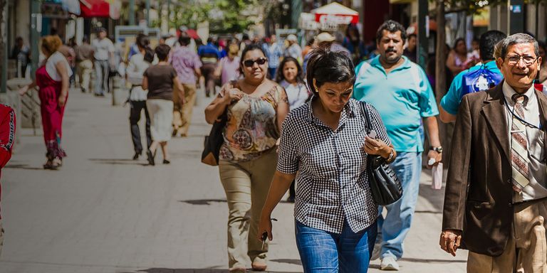People walking down a wide street in daylight - Inter American Development Bank - Impact Framework