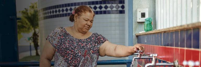 Woman turning on water tap - Inter American Development Bank - Water and Sanitation