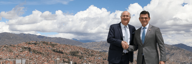 Ian Goldfjan shaking hands with another person, with a landscape in the background - Inter American Development Bank - IDB Group