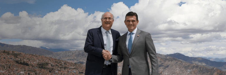 Ian Goldfjan shaking hands with another person, with a landscape in the background - Inter American Development Bank - IDB Group