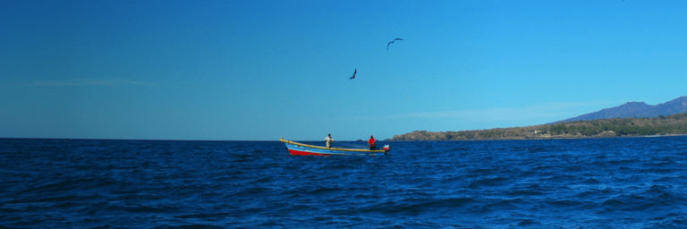 Panoramic view of a boat in the middle of the sea with mountains in the background - Inter American Development Bank - IDB Invest