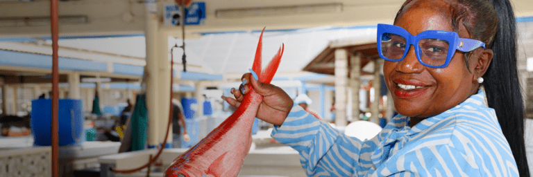 Woman smiling with a fish in their hands - Greater Access to Potable Water - Inter American Development Bank - IDB