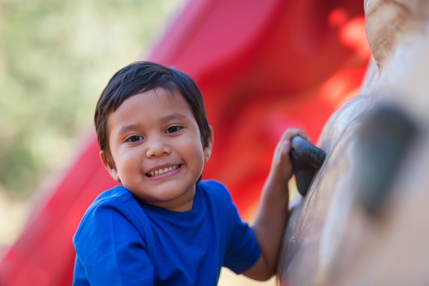 Um menino em um parque sorrindo para a câmera