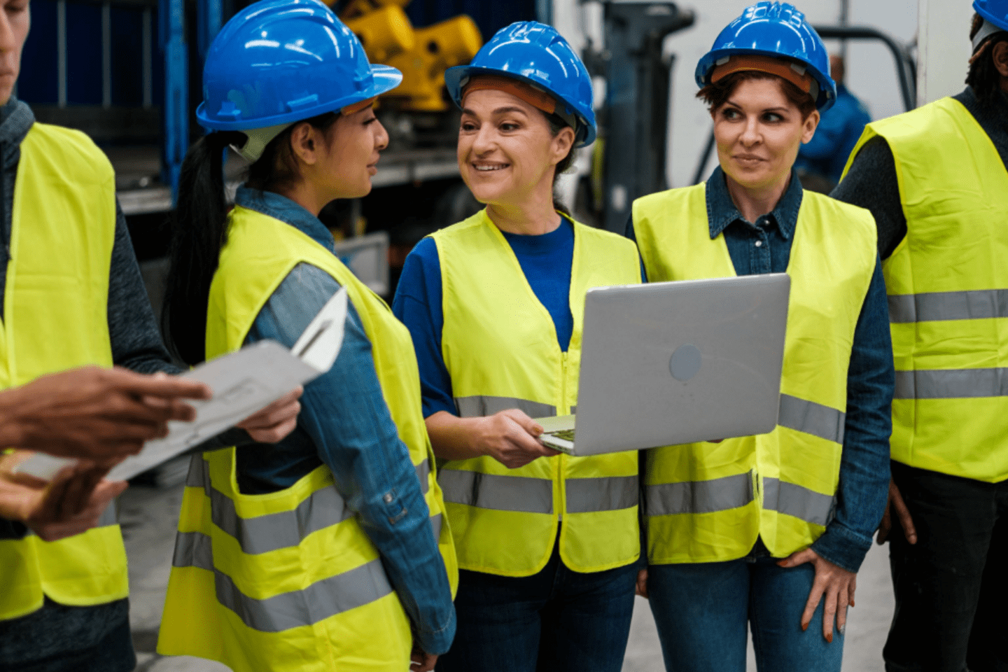 A group of multiracial engineers and workers in a factory wearing blue hard hats and yellow safety vests with technological innovation for solid waste management. 