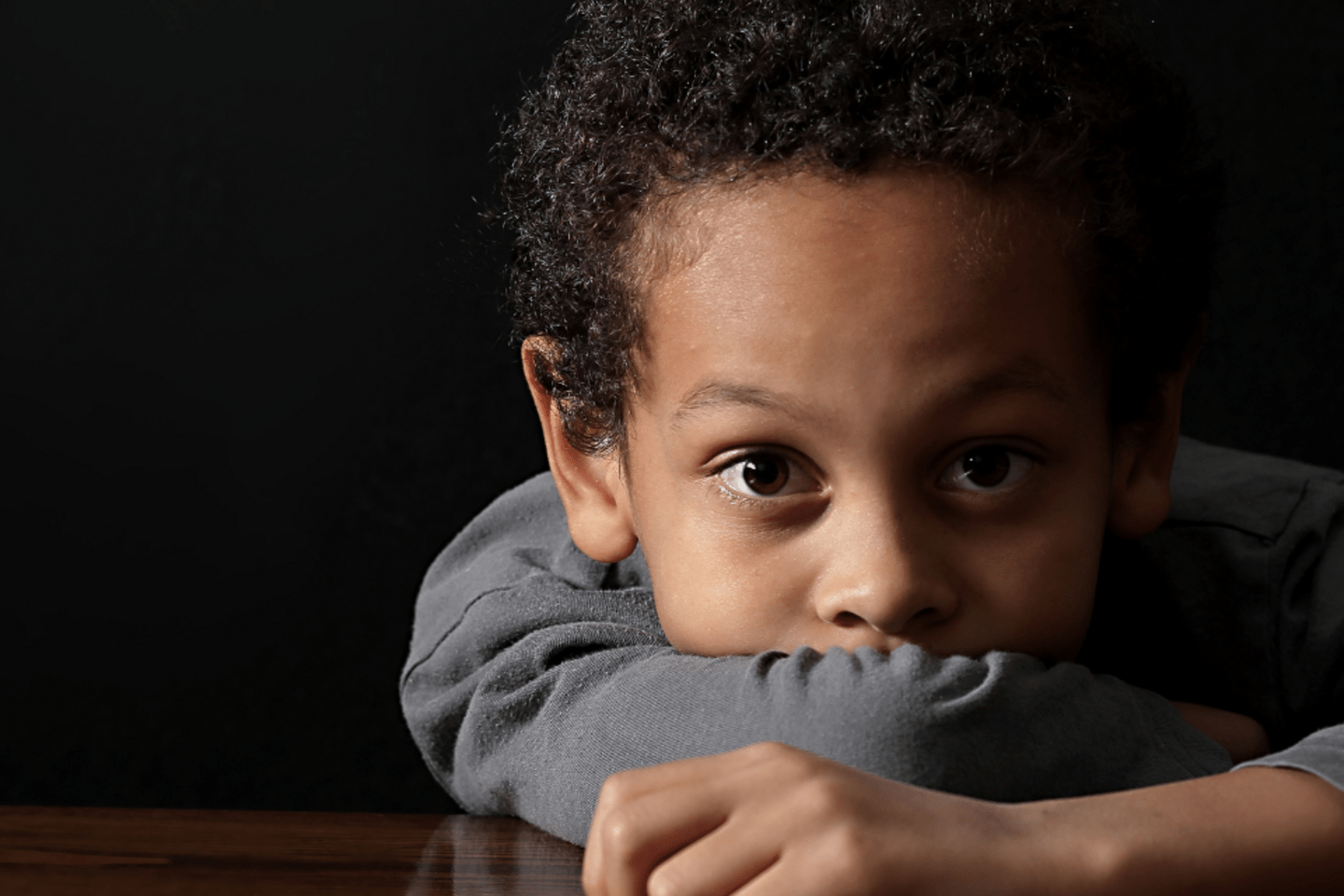 little boy looking to the camera. he is wearing a grey sweater