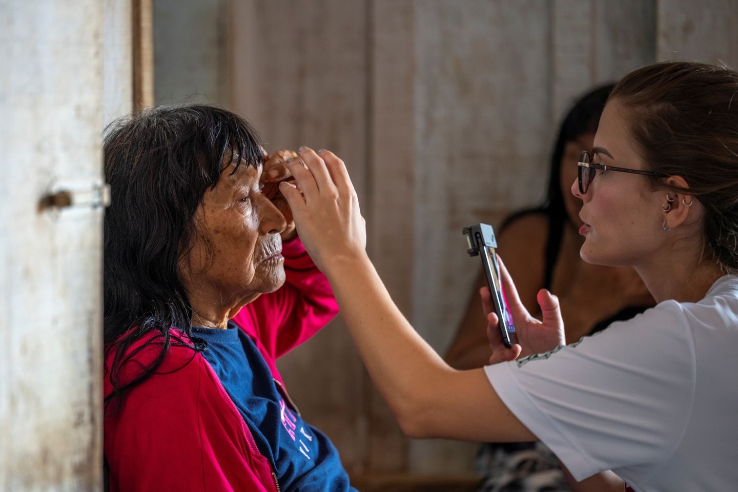 Female doctor performing an eye exam to an indigenous woman patient