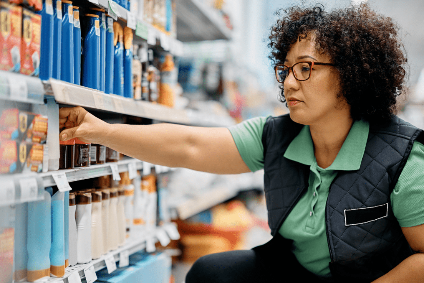 woman restocking shelf in supermarket 