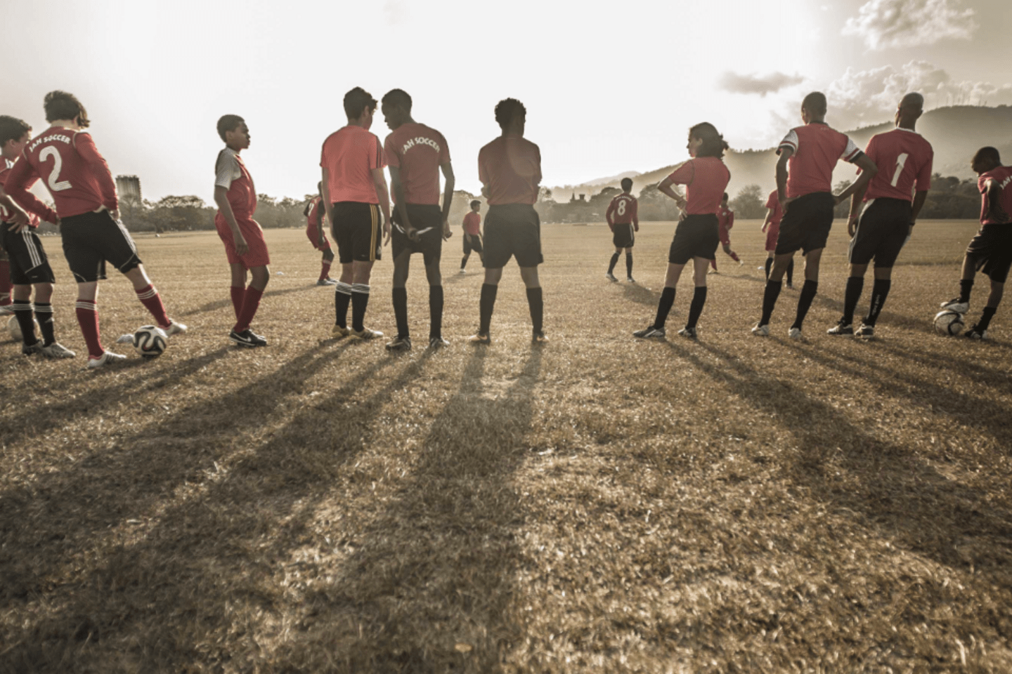 Personas jugando fútbol, en su gran mayoría hombres. Solo se ve claramente una mujer. 