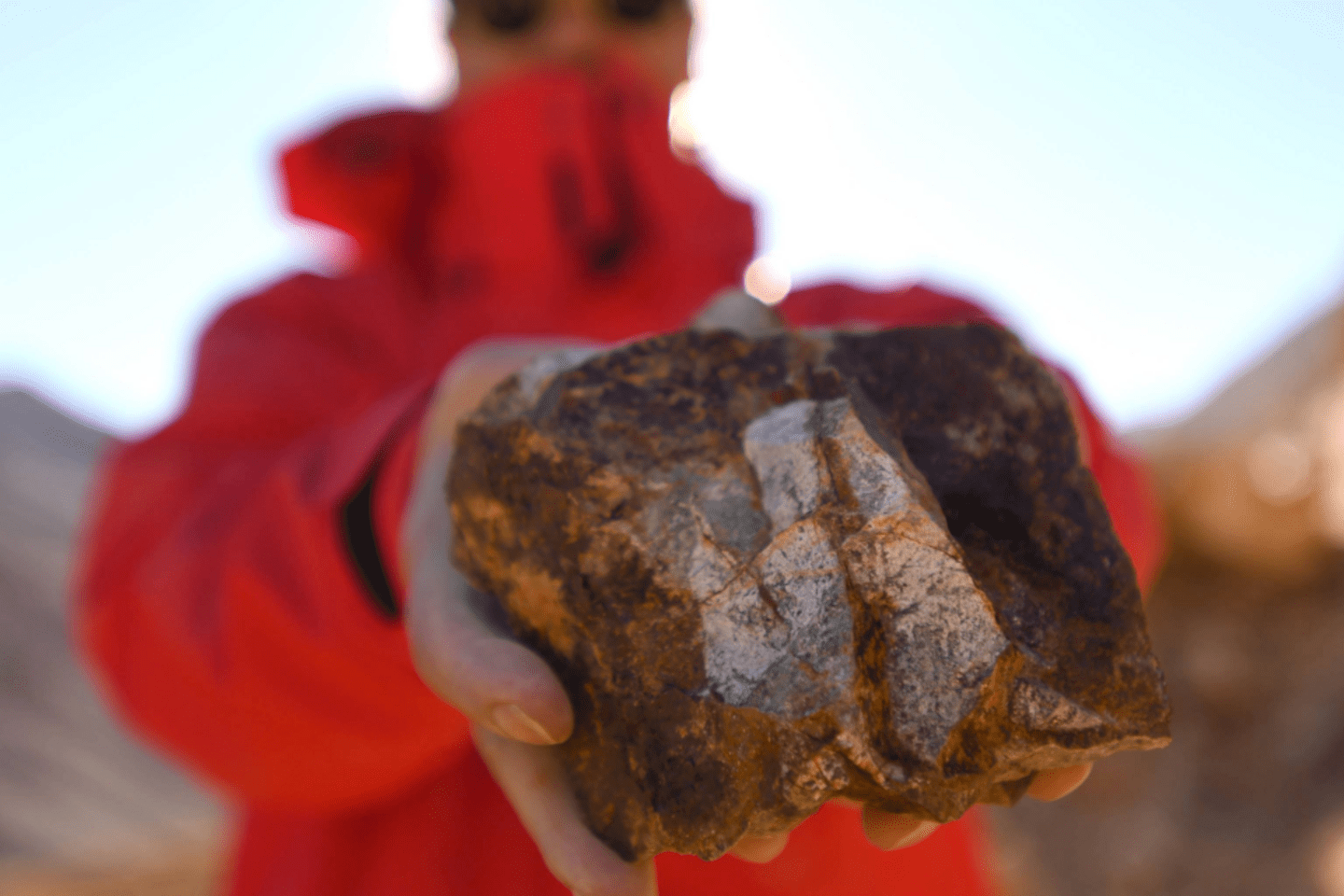 Muestra de mineral sostenida por una persona durante una actividad de exploración geológica. 