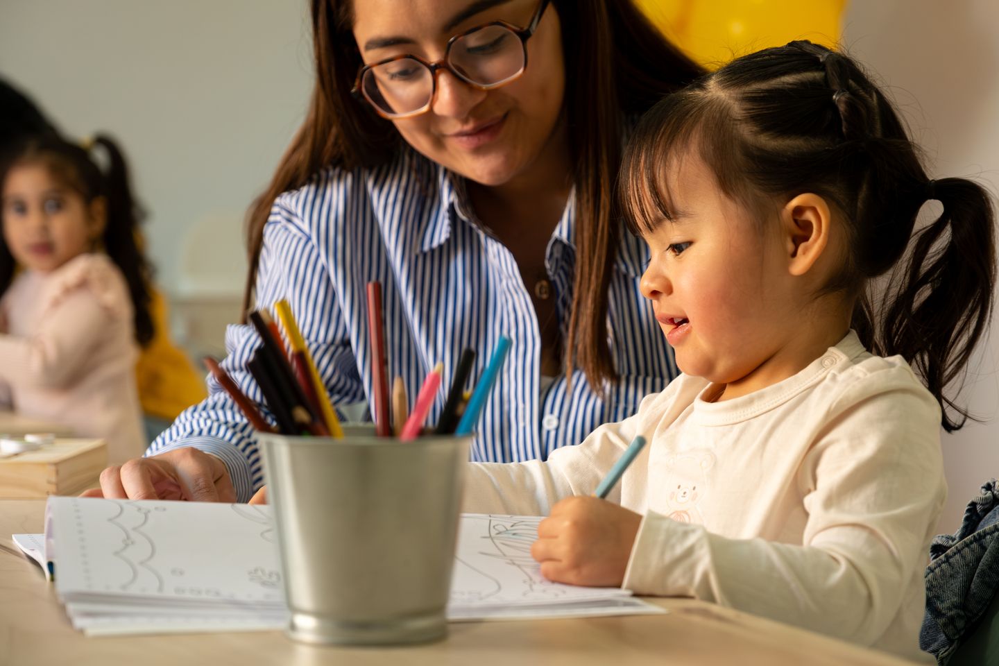 Young girl drawing with teacher 