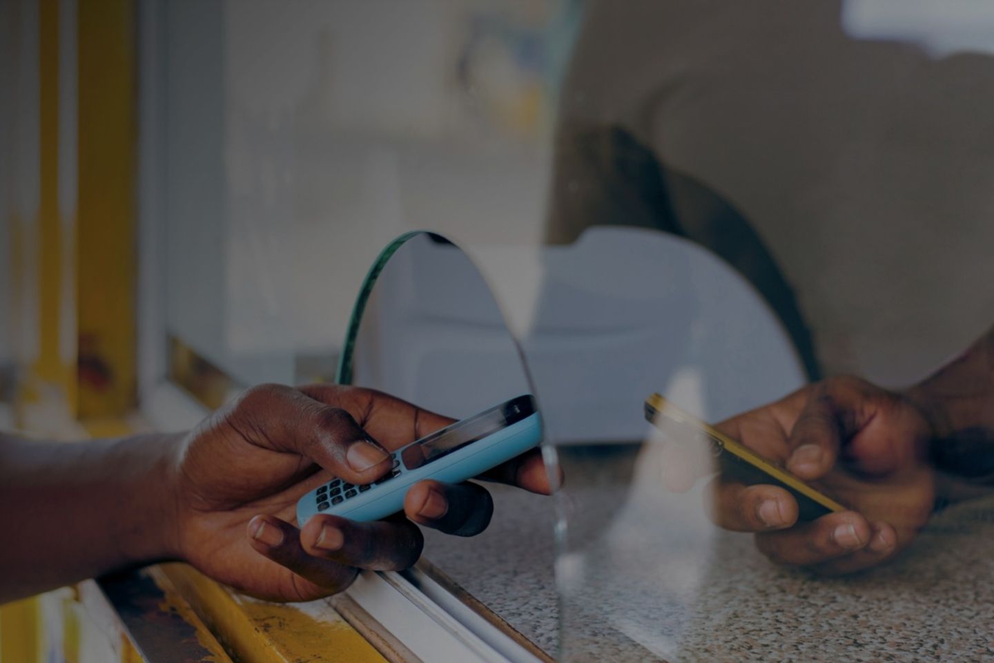 A person holds a cellphone in front of a counter.