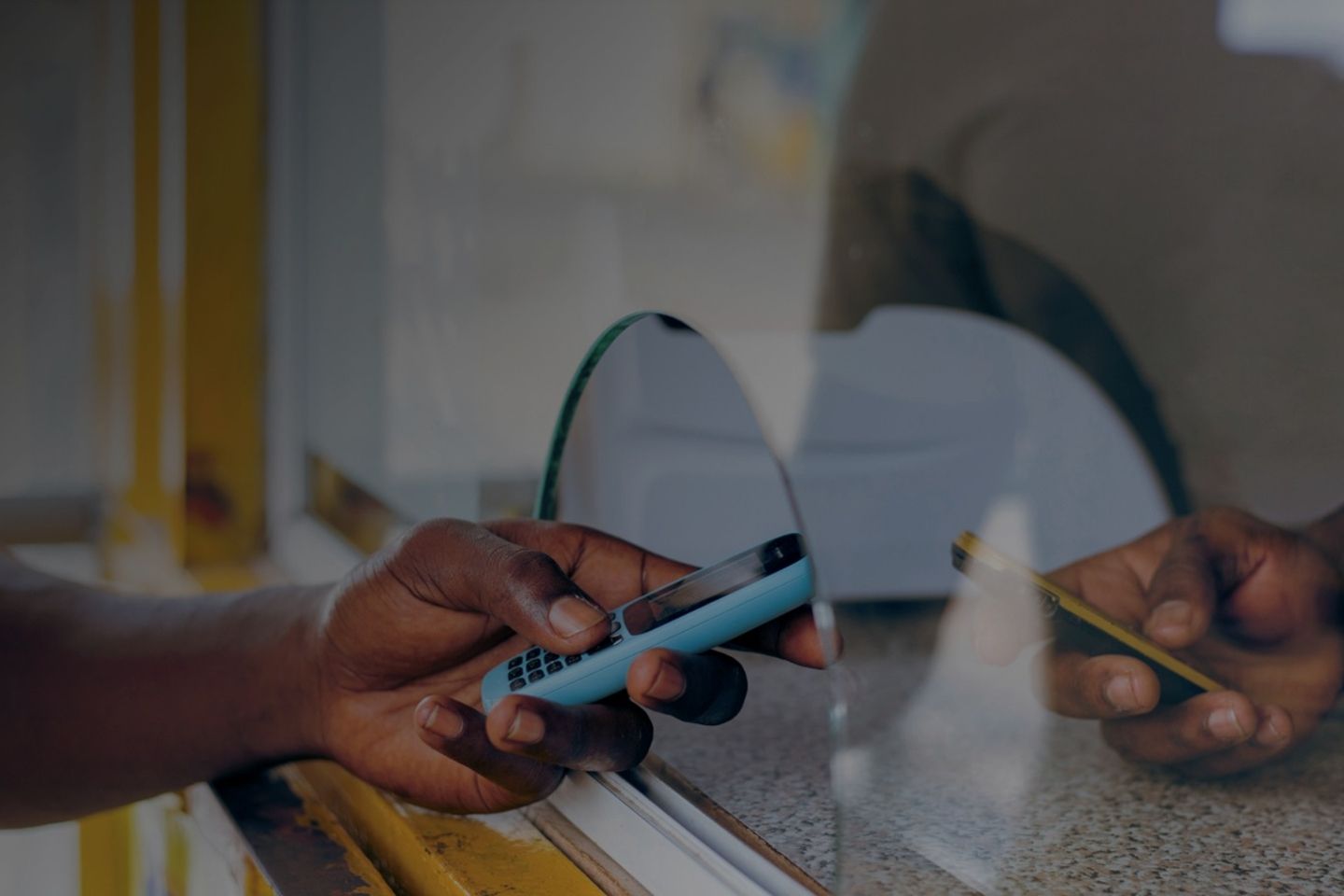 A person holds a cellphone in front of a counter.