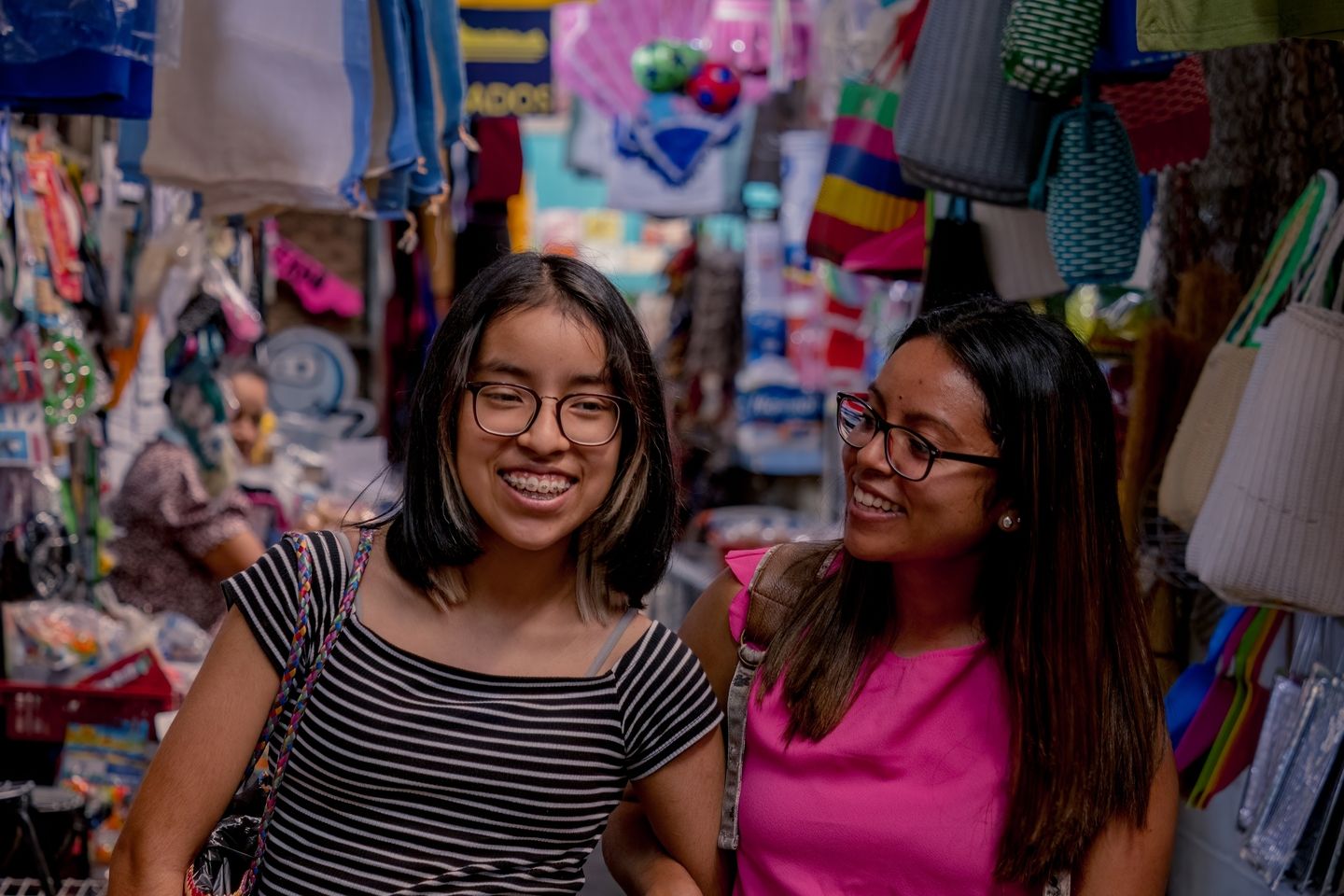Two Belizean young girls walking down a busy street in Belize and laughing