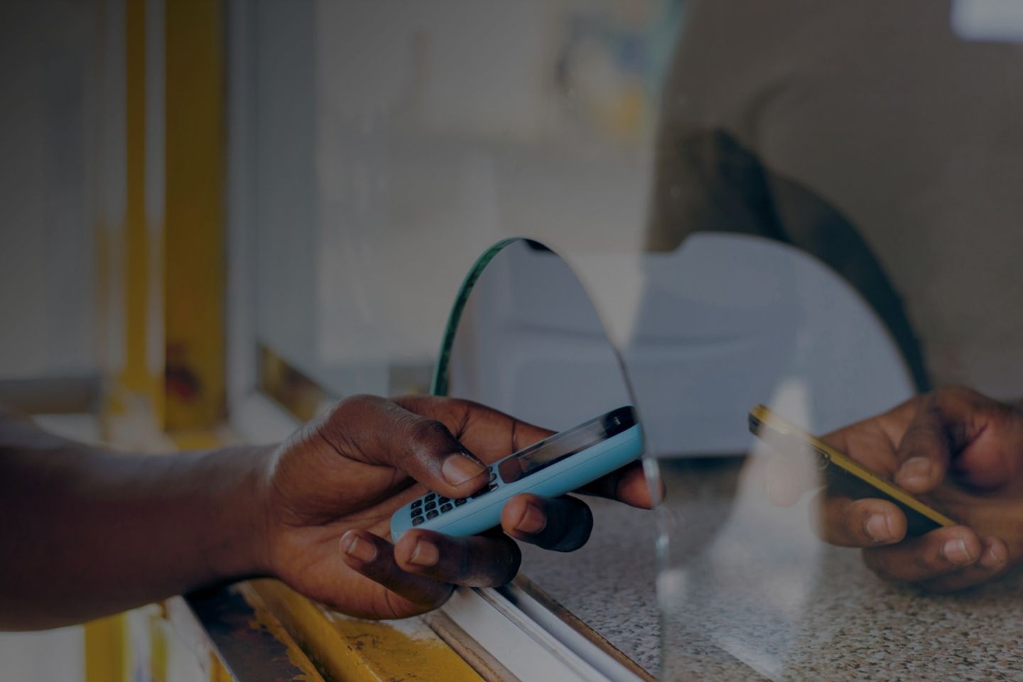 Persona con un celular en la mano en una ventanilla de atención.