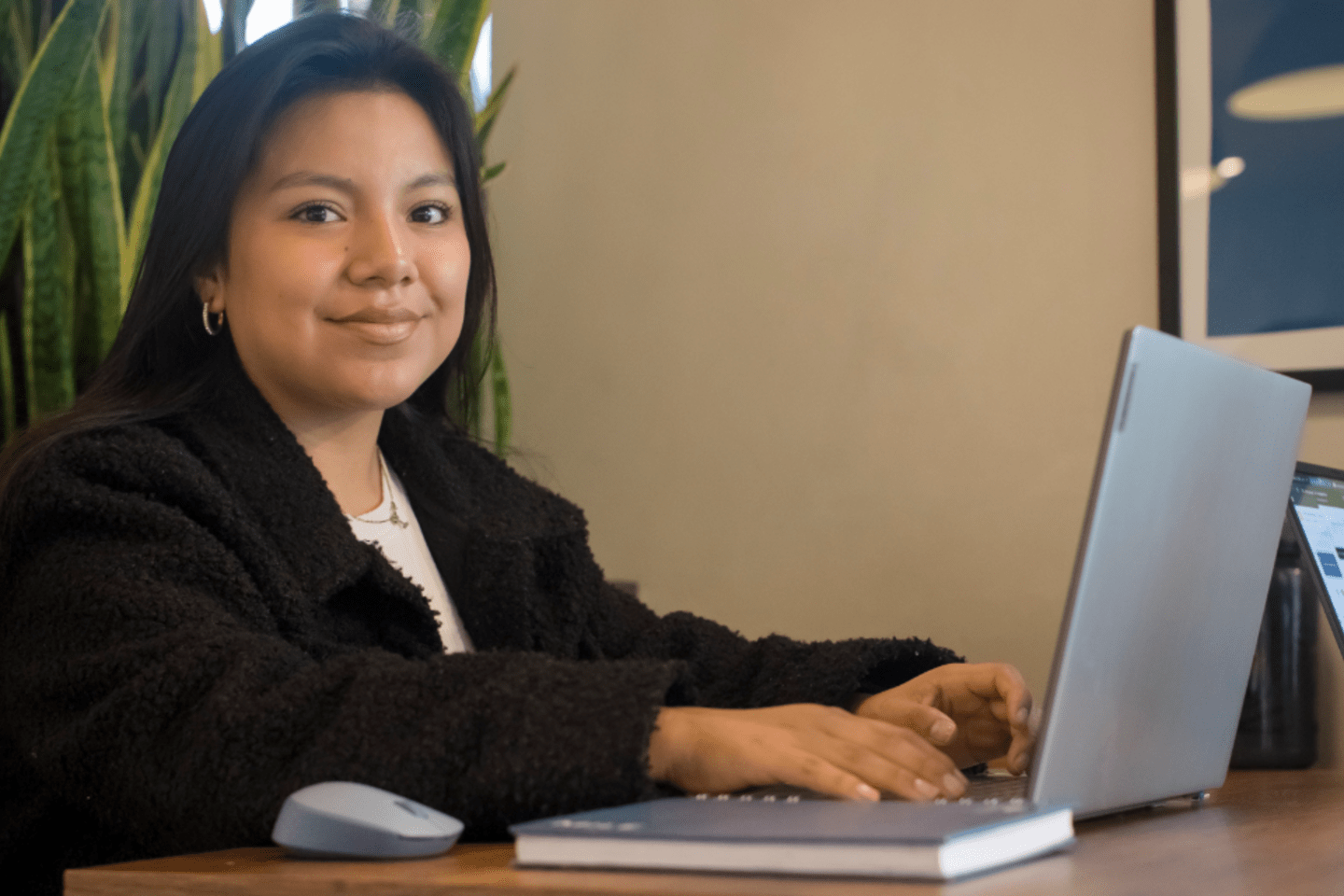 Mujer joven latinoamericana trabajando en una laptop.