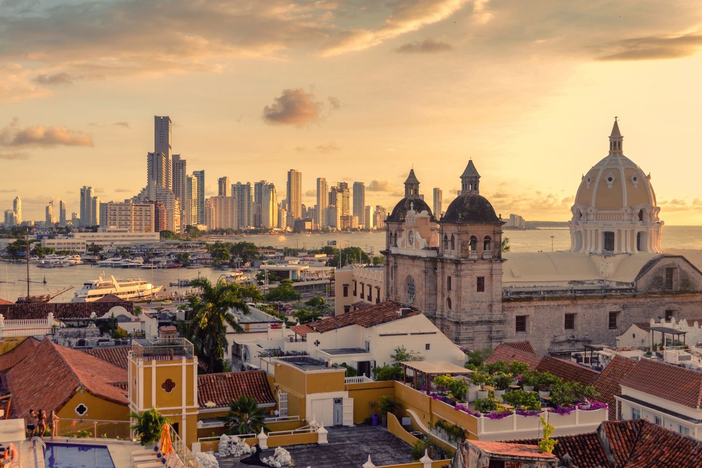 Aerial view of the historic center of Cartagena de Indias, Colombia, with the modern skyline in the background and the sea beyond.