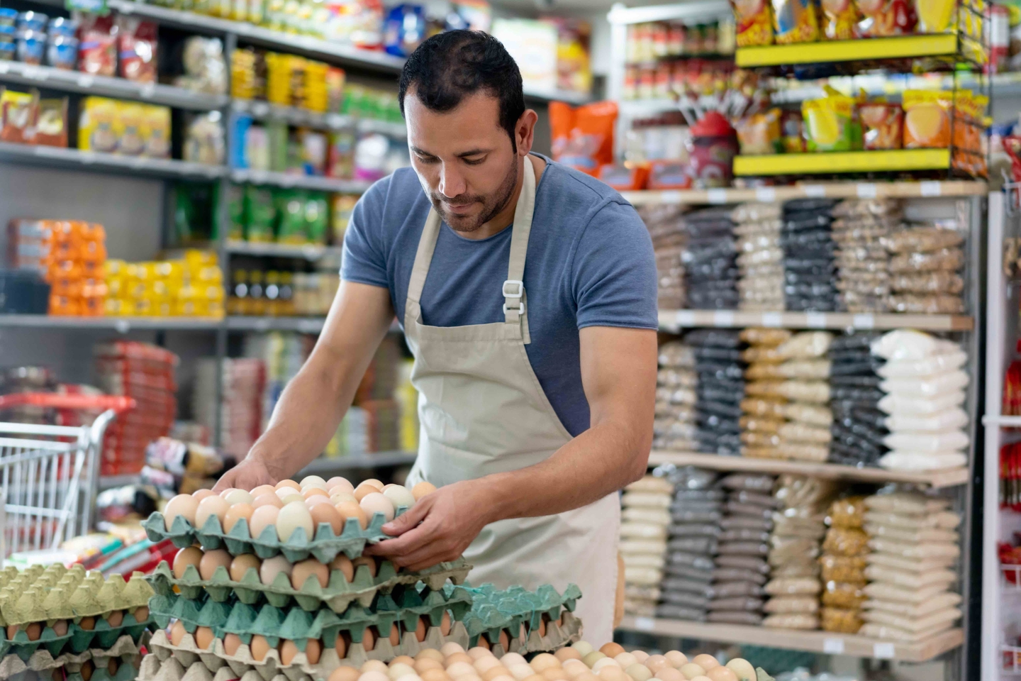 Latin american male business owner of a small market arranging the egg display