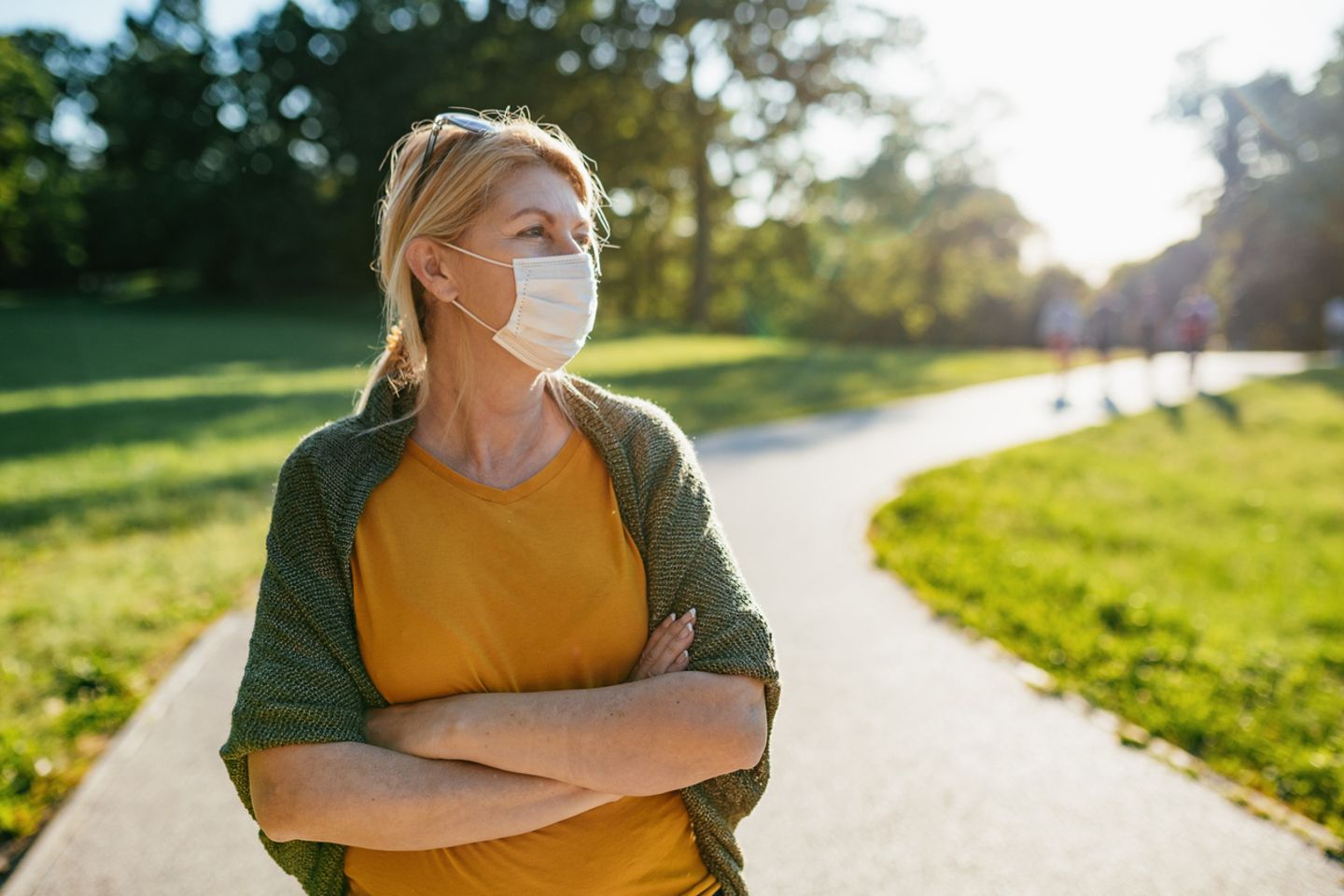 Senior woman outdoors on spring day, keeping social distance with face mask on
