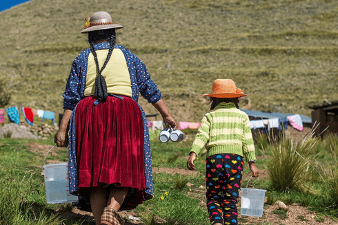 an indigenous mother with her daughter walking along a path in the countryside
